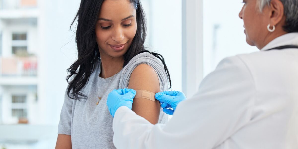 a woman getting a shot to make sure she meets the vaccination requirements for traveling abroad