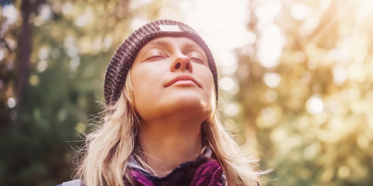 a woman standing in a forest enjoying fresh air in one of the healthiest countries in the world