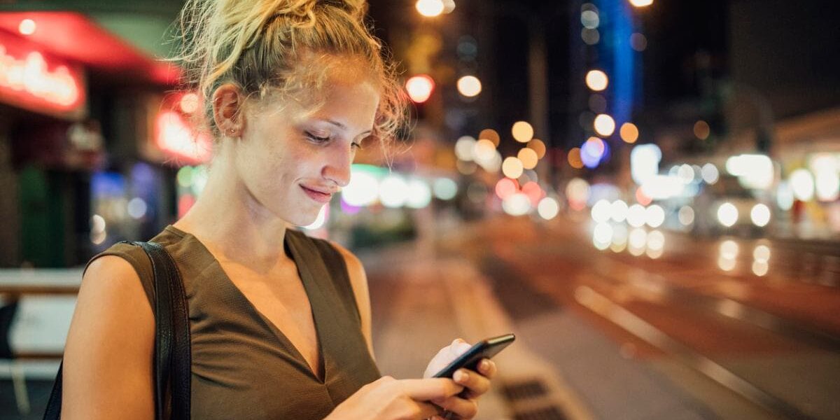 a woman booking an Uber on her cell phone at night