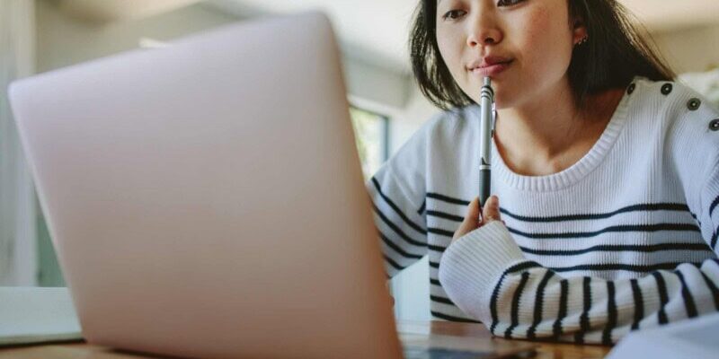 a woman researching travel insurance on her laptop after asking does my health insurance cover international travel