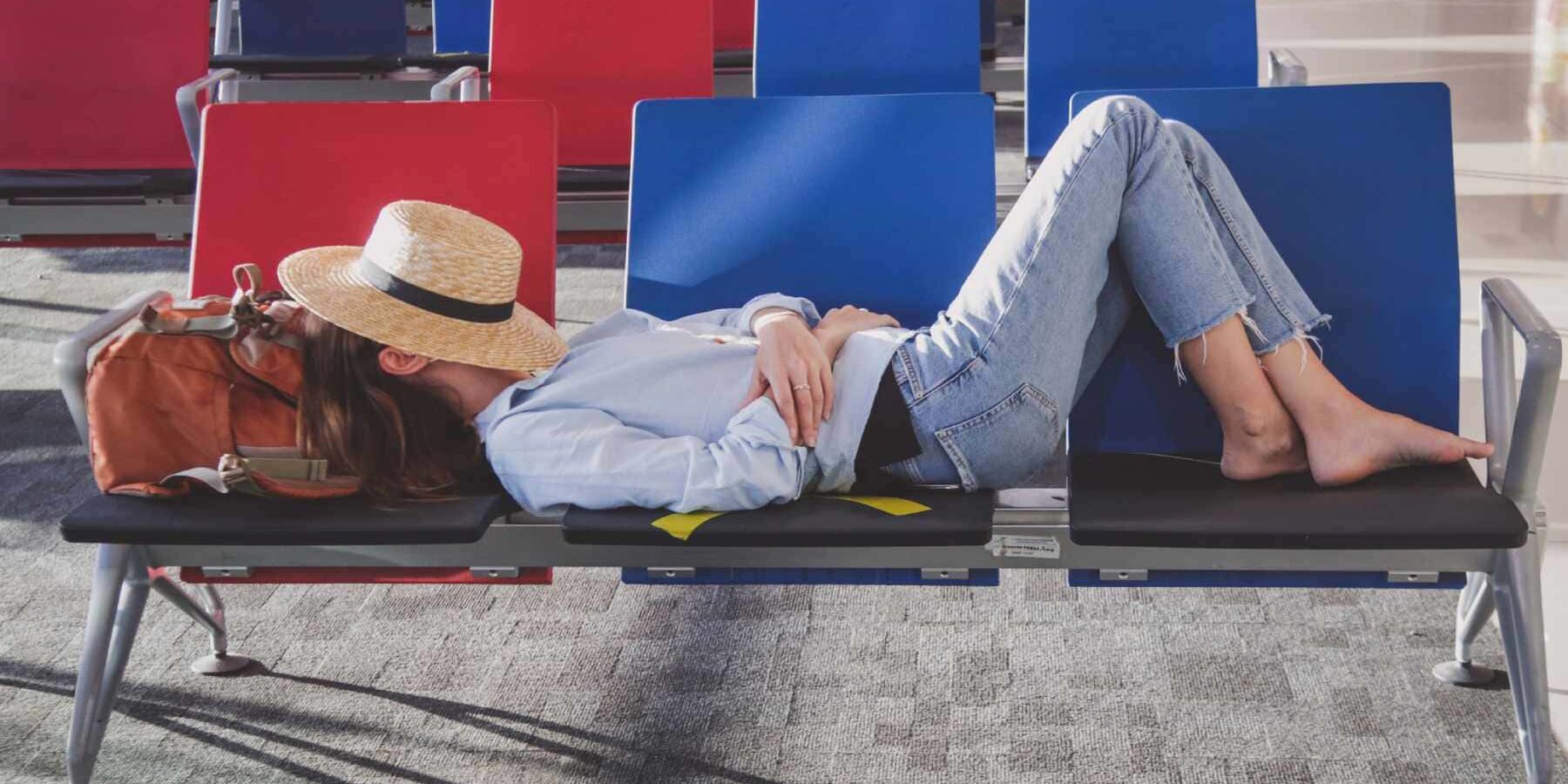 a tired woman taking a nap in an empty airport while she waits for her flight